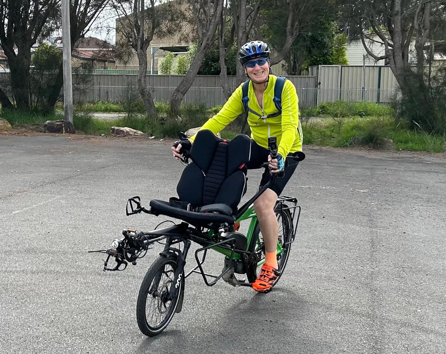 A smiling man piloting a green recumbent tandem during Pino training.