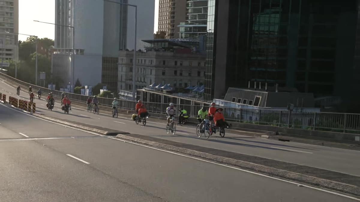 Cyclists riding along the Cahill Expressway beneath the city towers in morning light.