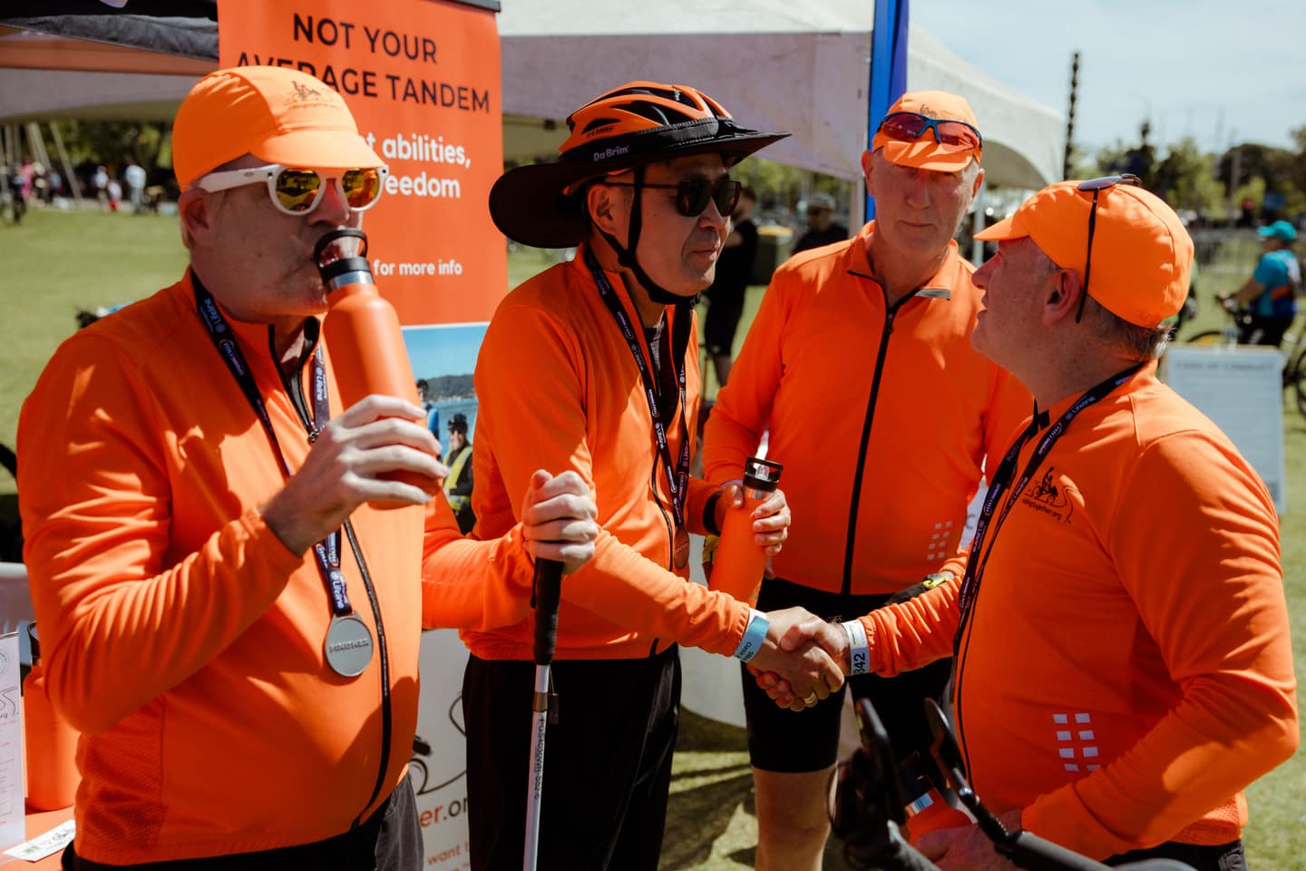 A smiling rider takes a selfie of the group enjoying a break by the water.