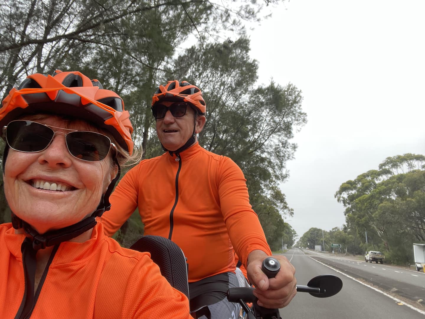 A woman rider smiling on the front of a tandem, taking a selfie with her pilot Garry Taunton.