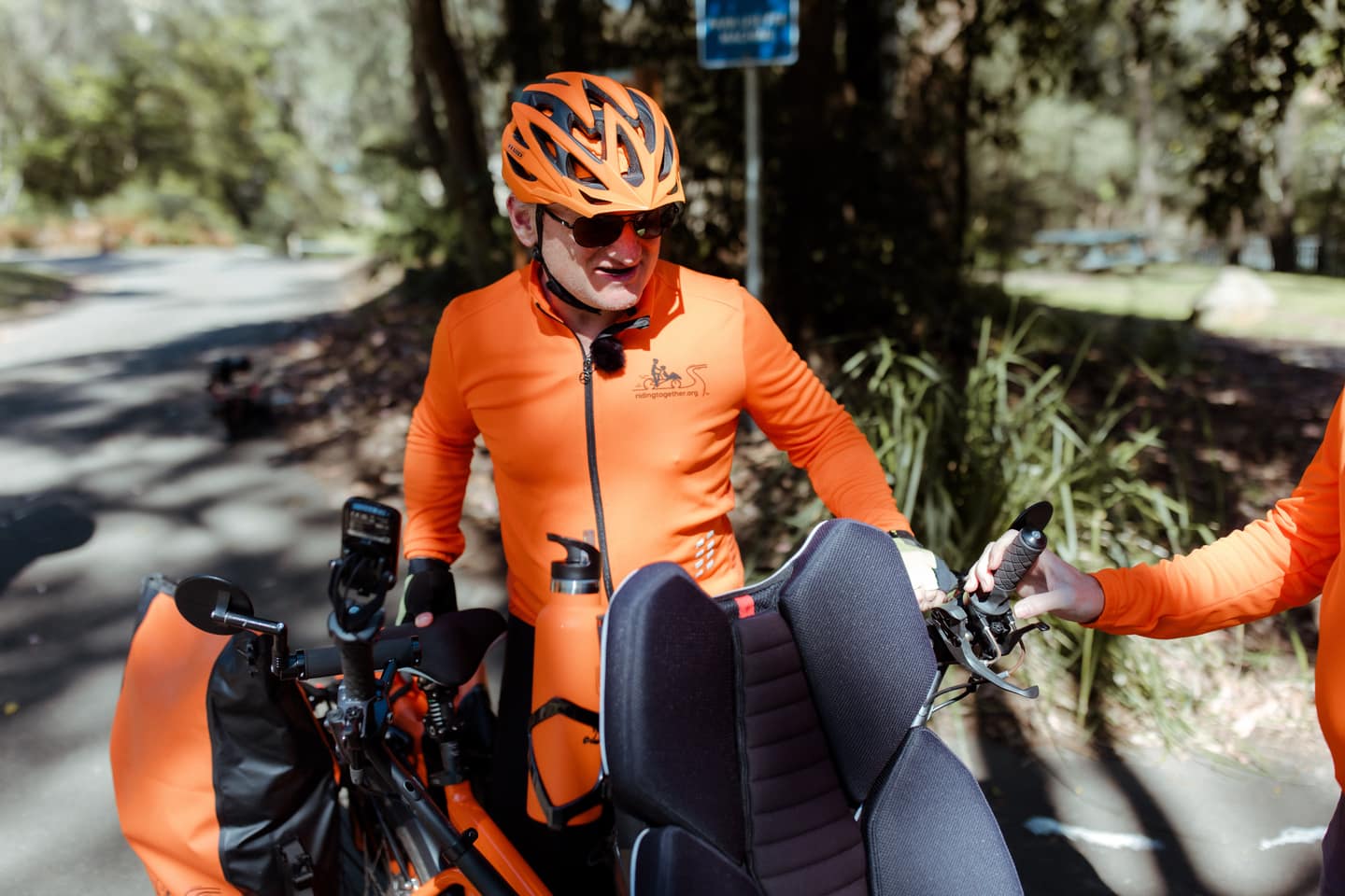 Two pilot volunteers laughing as they unload tandem bikes from a trailer.