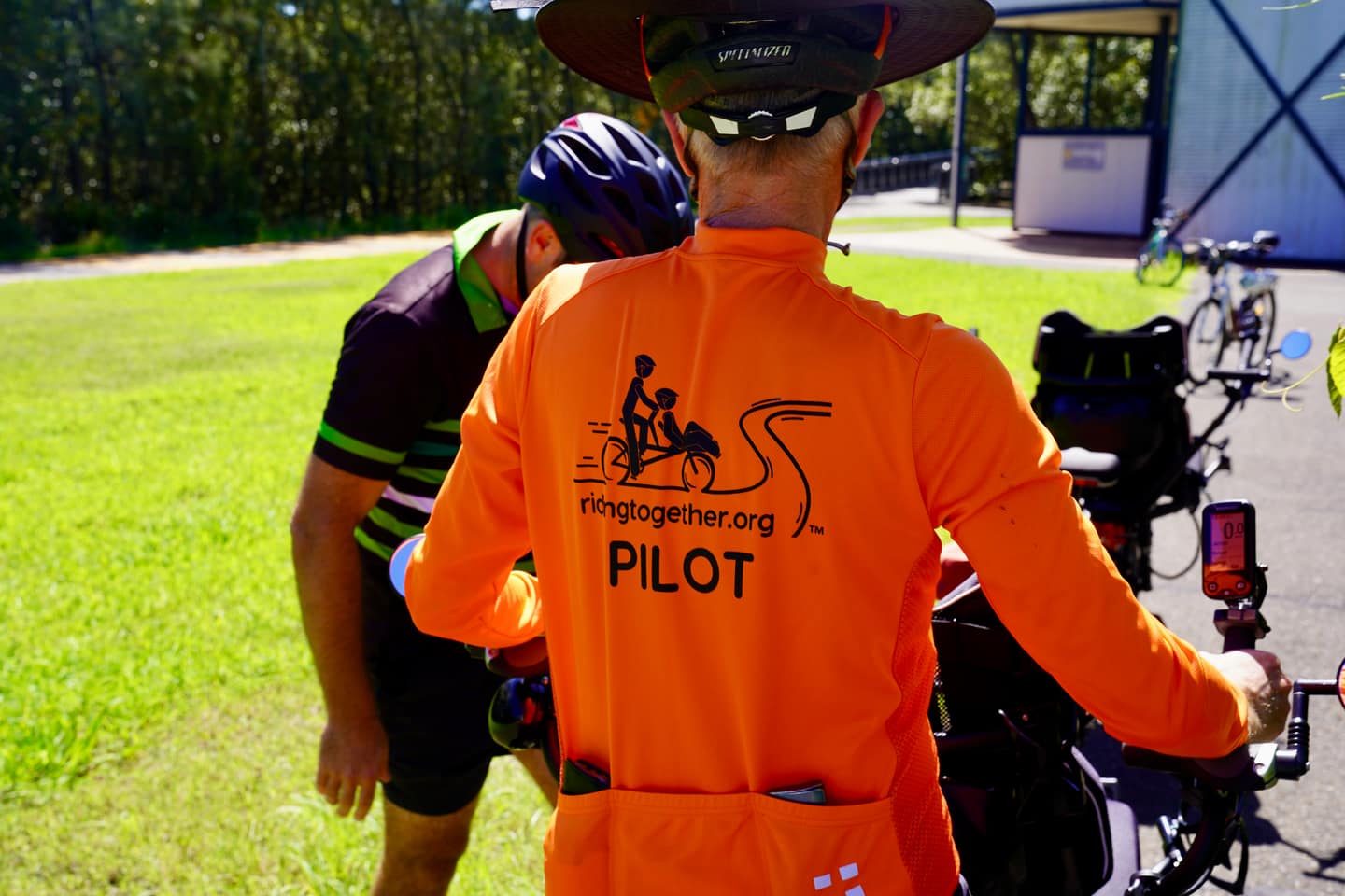 Two pilot volunteers laughing as they unload tandem bikes from a trailer.